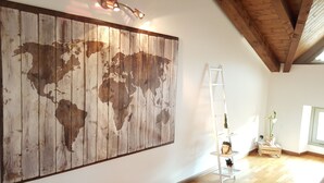 A room with a large wooden world map mural, a white ladder, and a small plant on a white shelf. - Donizetti Royal (Bergamo)