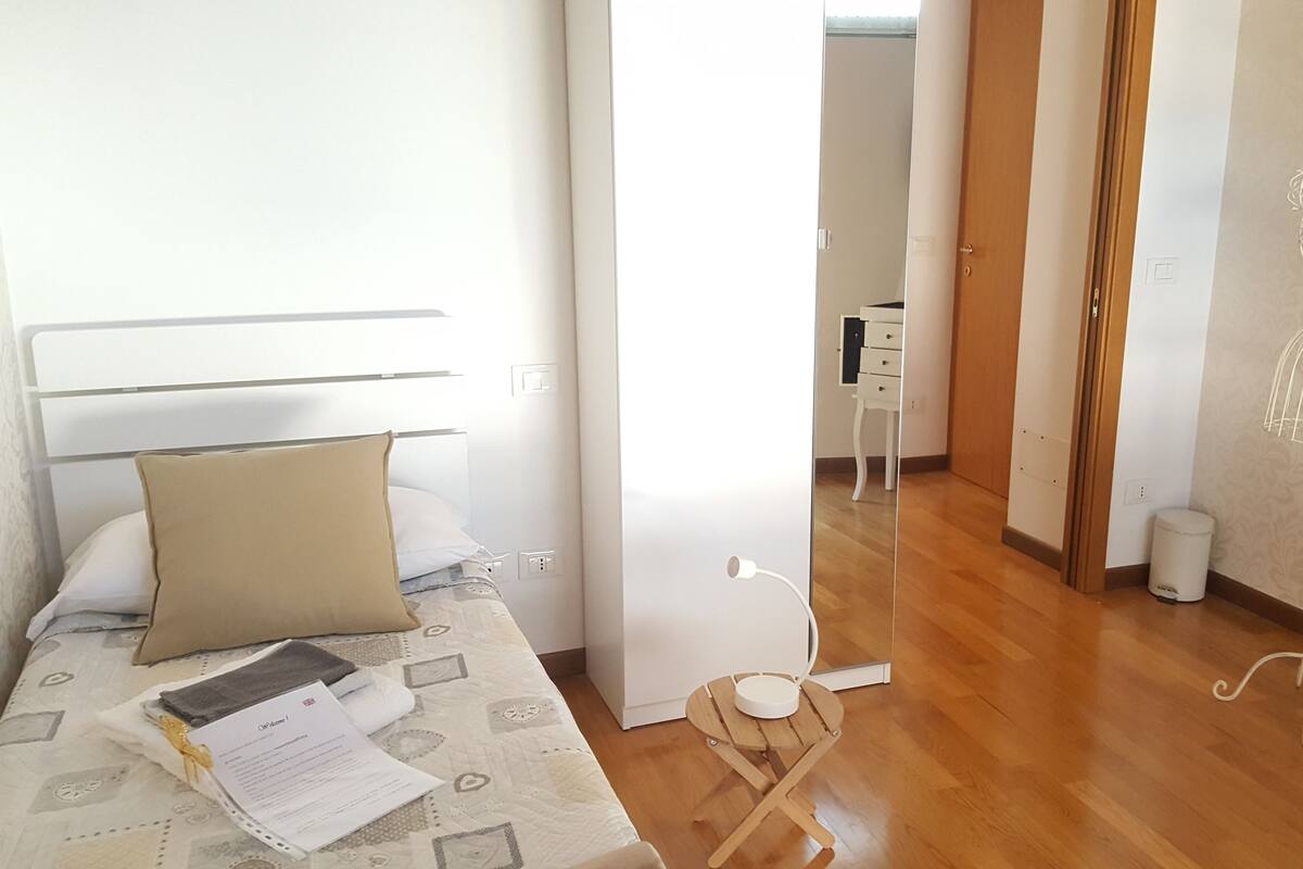 A neatly arranged bedroom with a bed, a bedside table with a lamp, and a wardrobe.