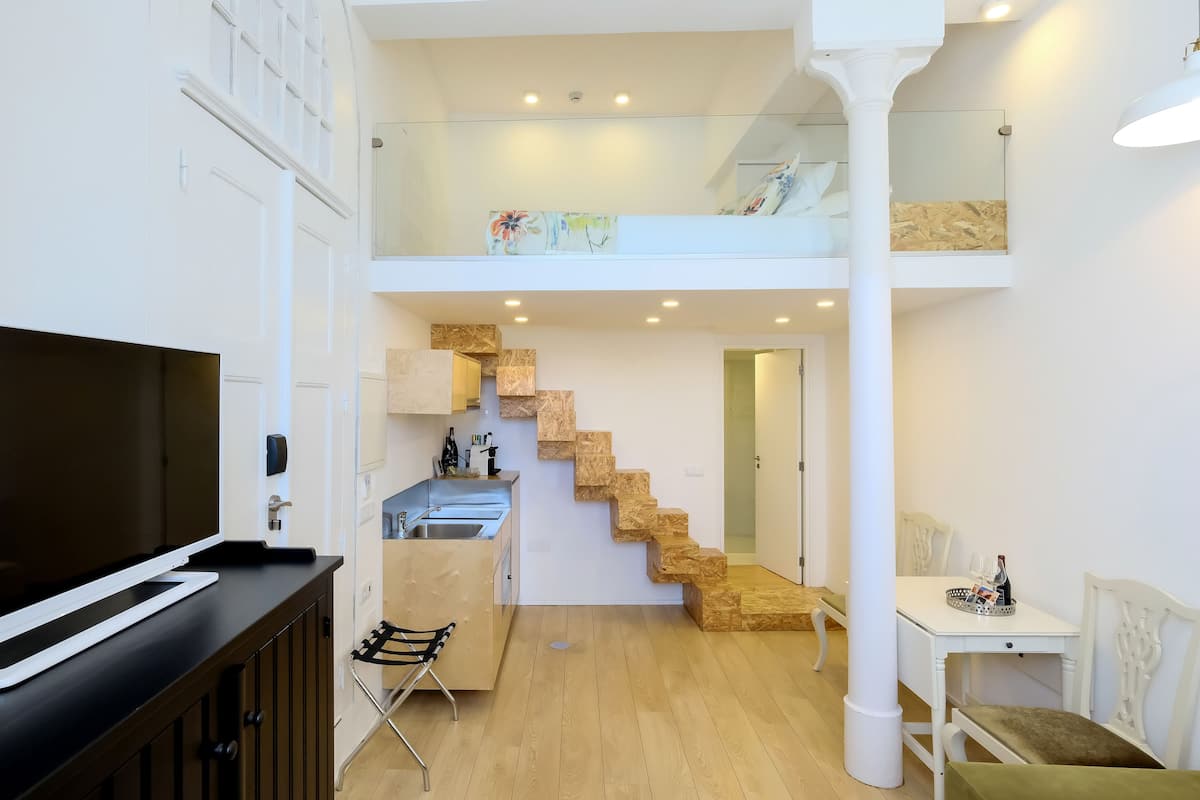 A modern apartment with a kitchen, dining area, and a staircase leading to an upper level.