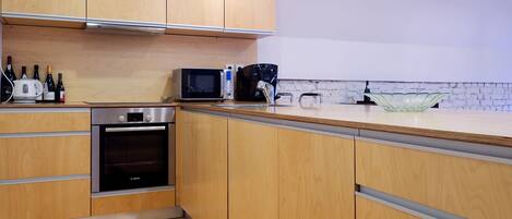 A modern kitchen with wooden cabinets, stainless steel appliances, and a glass bowl on the counter.