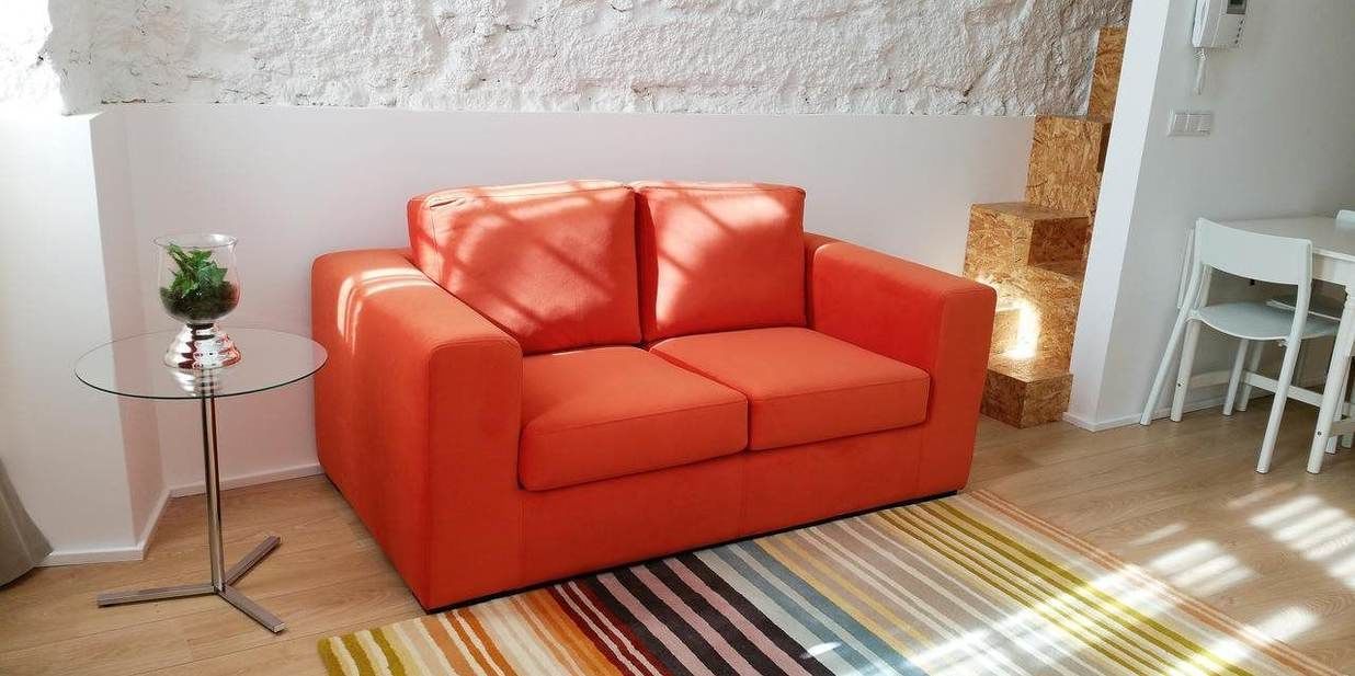 Una sala de estar moderna con un sof á rojo, una mesa de centro de cristal y una alfombra a rayas.