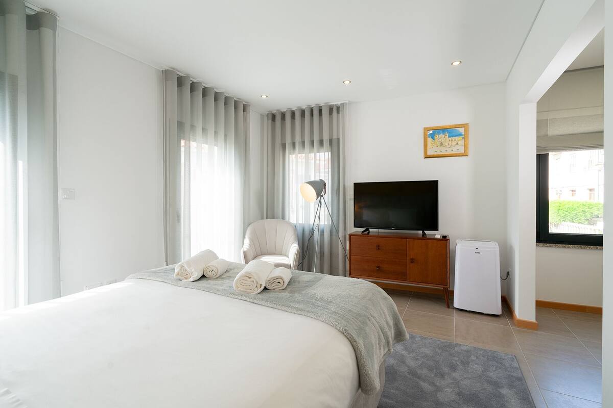 A hotel room with a bed, a TV, a desk, and a window.