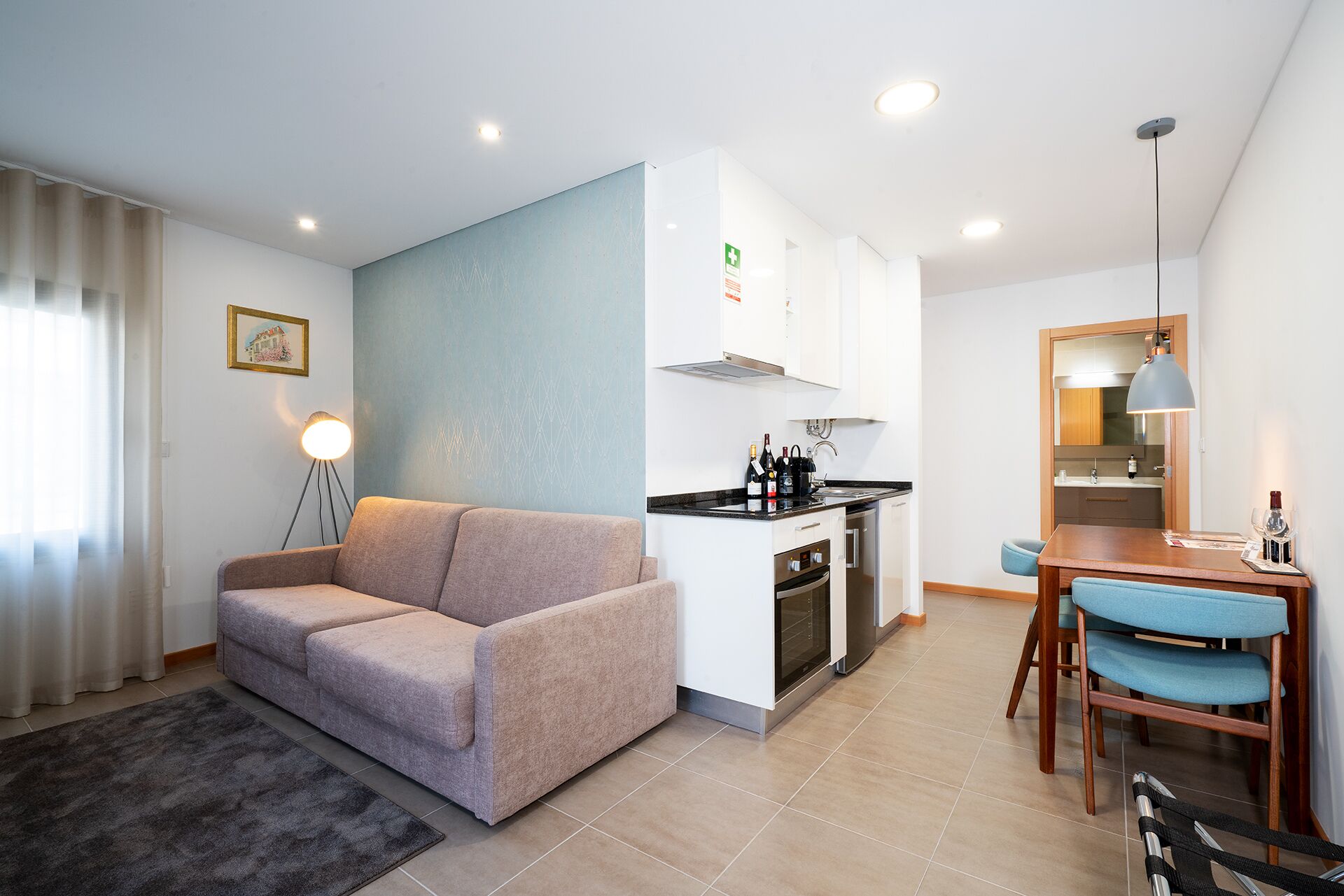 Un espacio habitable compacto con kitchenette, un sofá, una mesa de comedor con sillas y una pequeña zona de cocina.
