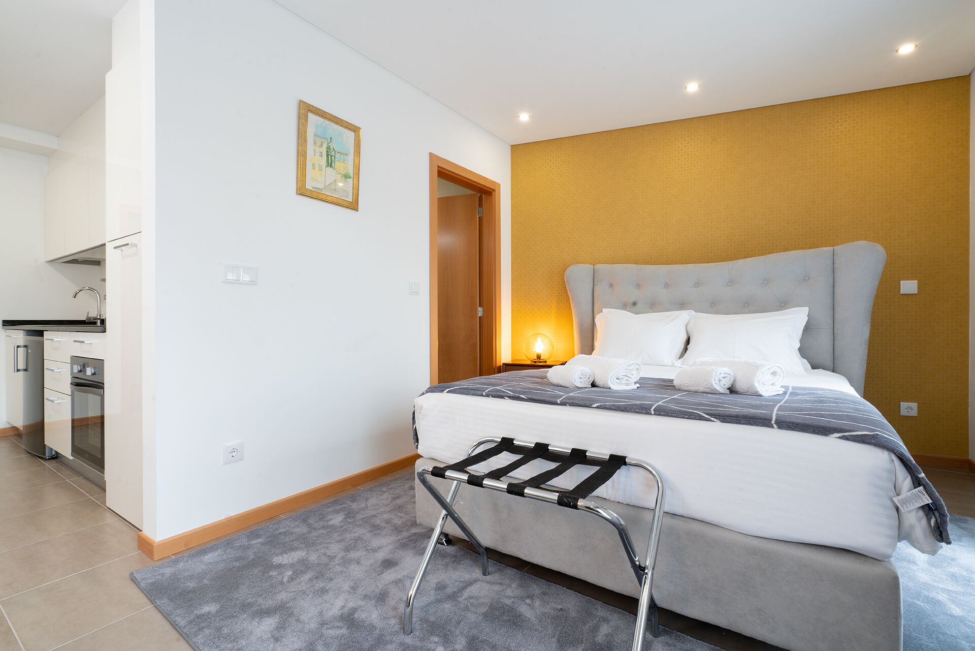 A modern hotel room with a bed, a small desk, and a bathroom.