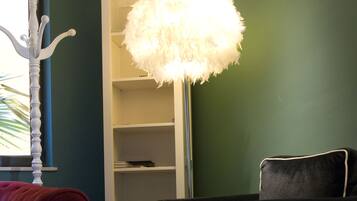 Une pièce avec une bibliothèque blanche, un fauteuil noir, un fauteuil rouge et une table blanche.