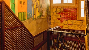 A staircase with a wooden handrail and a wall with a mural of colorful buildings. - Sweet Home (Salamanca)