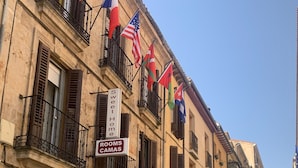 A building with multiple balconies, flags, and a sign indicating 'Sweet Home' and 'Rooms CAMAS'. - Sweet Home (Salamanca)