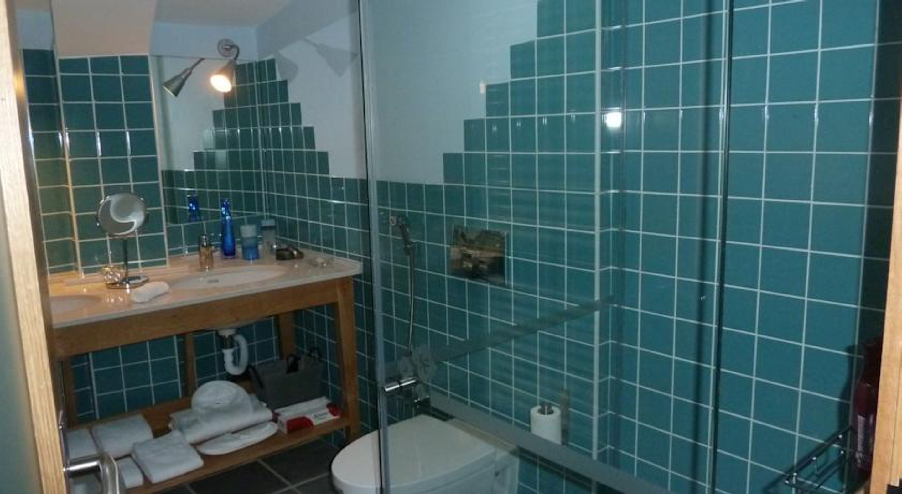 A bathroom with a sink, mirror, and shower area.