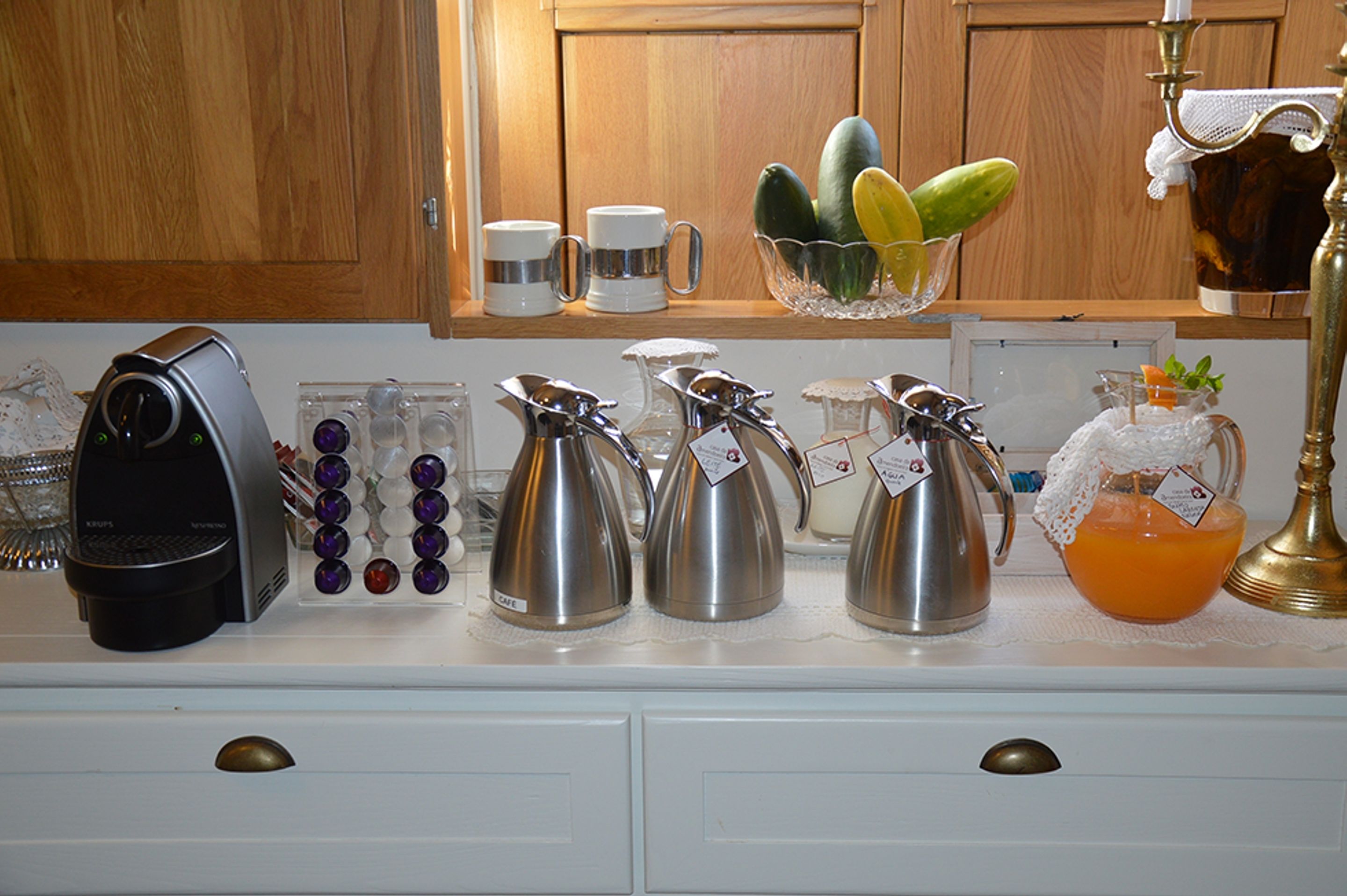Una encimera de cocina con varias cafeteras, una máquina de café y una jarra de jugo de naranja.