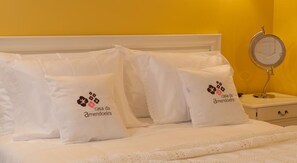 Una cama con ropa de cama y almohadas con el logo 'casa da amendoeira'.