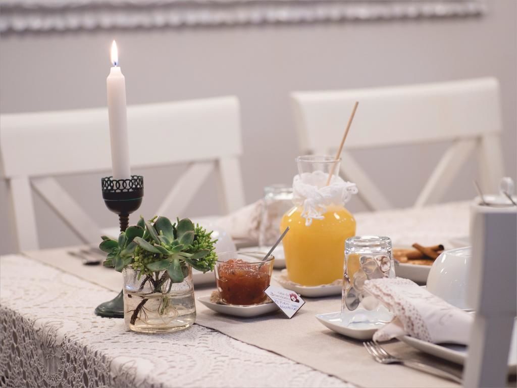 A table set with a candle, a glass of orange juice, a small dish of jam, and a glass of water.