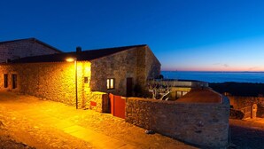 Un edificio de piedra con entrada empaveda y vista al mar al atardecer.