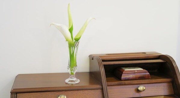 Una mesita de noche de madera con un florero de vidrio transparente que contiene flores blancas.