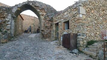 A stone building with an archway entrance, a cobblestone path, and a sign indicating 'casa da amendoeira'.