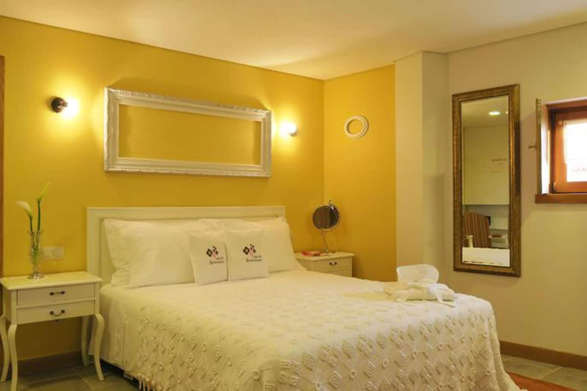 Una habitación de hotel con cama, mesitas de noche, un espejo y una ventana.
