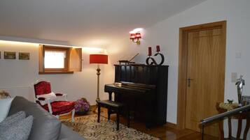 A living room with a piano, a red armchair, a sofa, and a lamp.