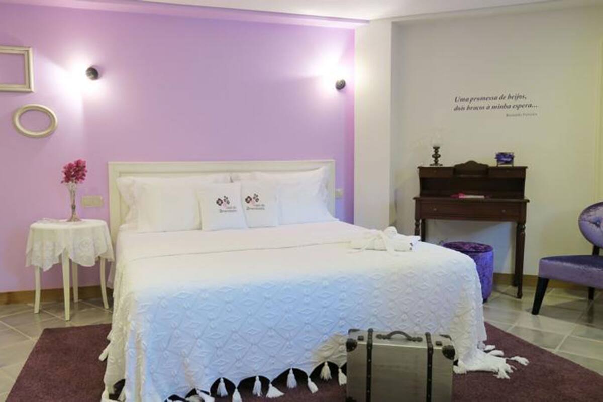 Un dormitorio con cama, mesita de noche, escritorio, silla y una pared con una cita.