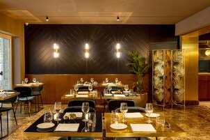 Un restaurante con mesas dispuestas para comer, una pared decorativa y una planta.