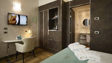 Una habitación de hotel con cama, escritorio, silla, televisión y baño.