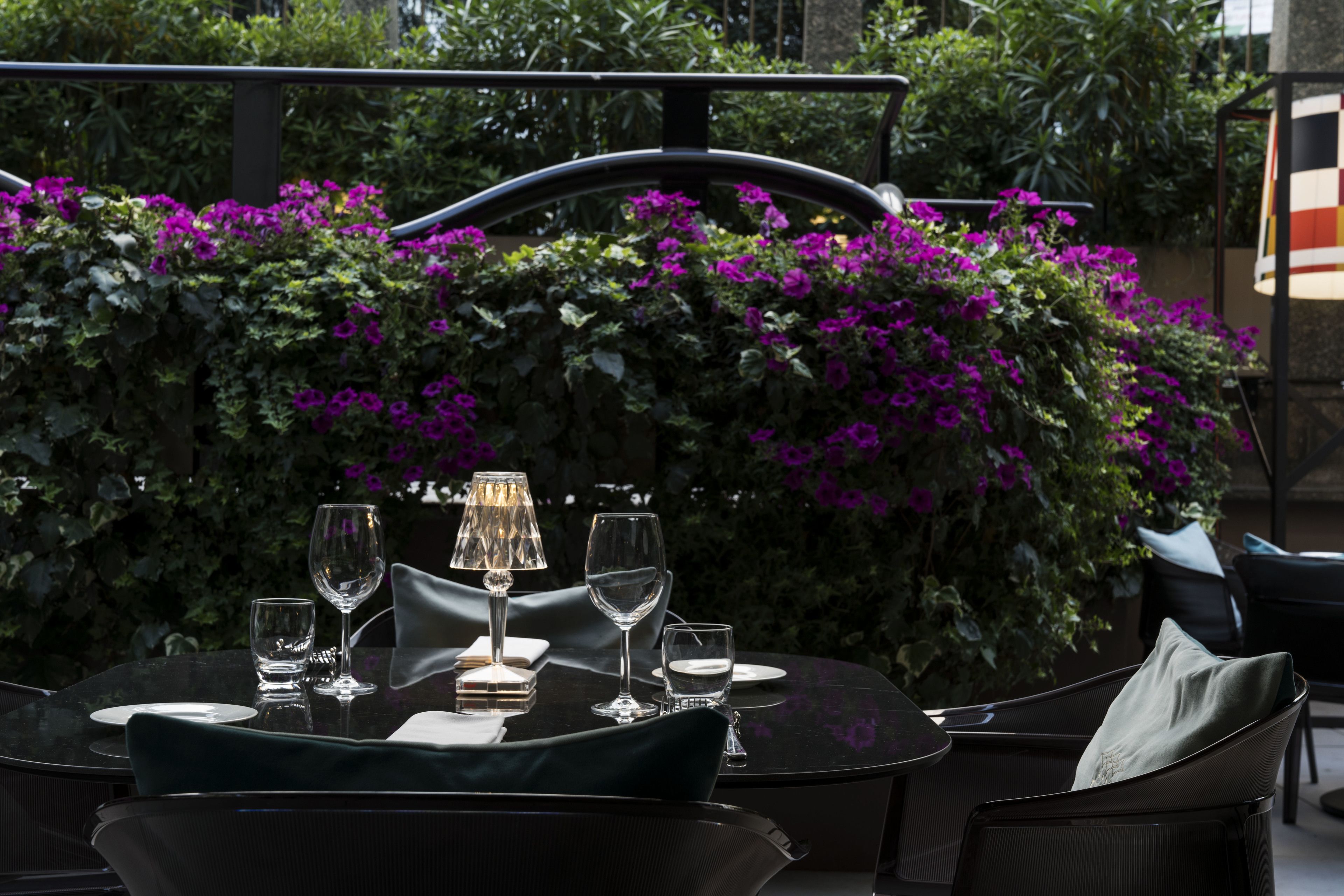 A round table set for dining with chairs, a glass of water, and a wine glass.