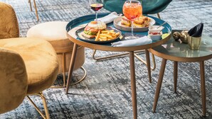 Comedor con mesas redondas, sillas y un recipiente tipo bufé con comida y bebidas.