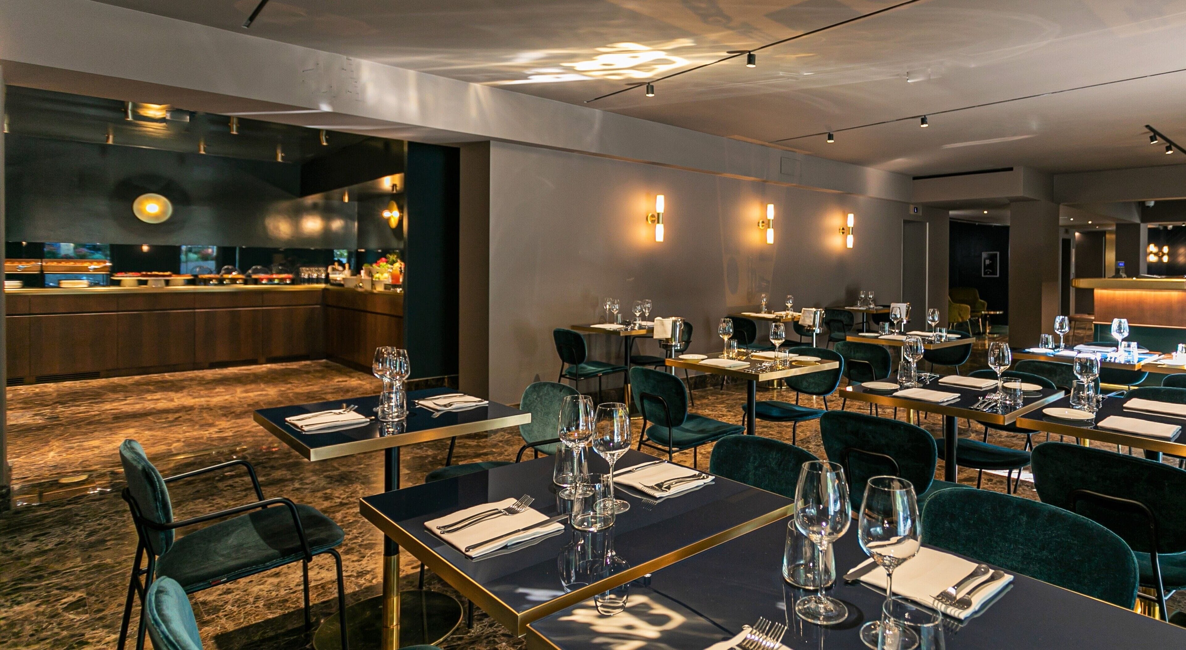 A restaurant with tables set for dining, a bar area, and a kitchen in the background.