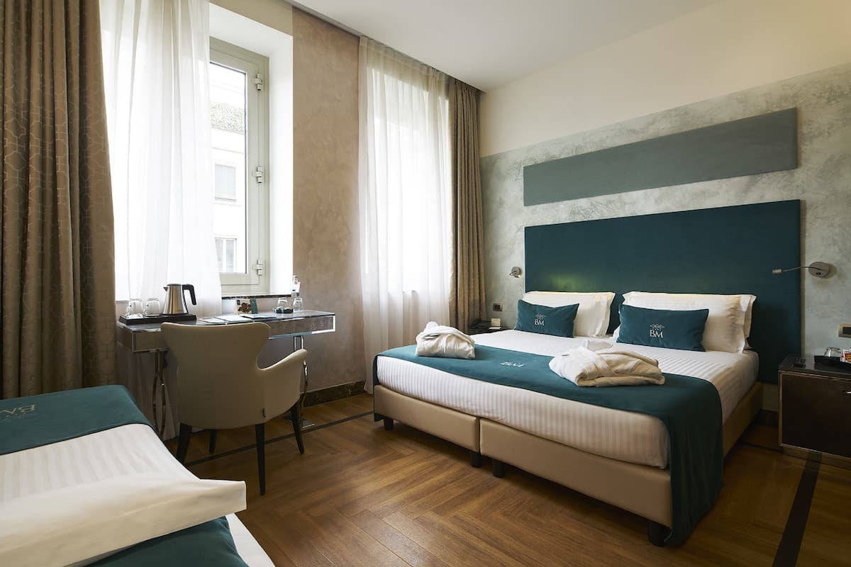 Una habitación de hotel con una cama, un escritorio, una silla y vistas al exterior.