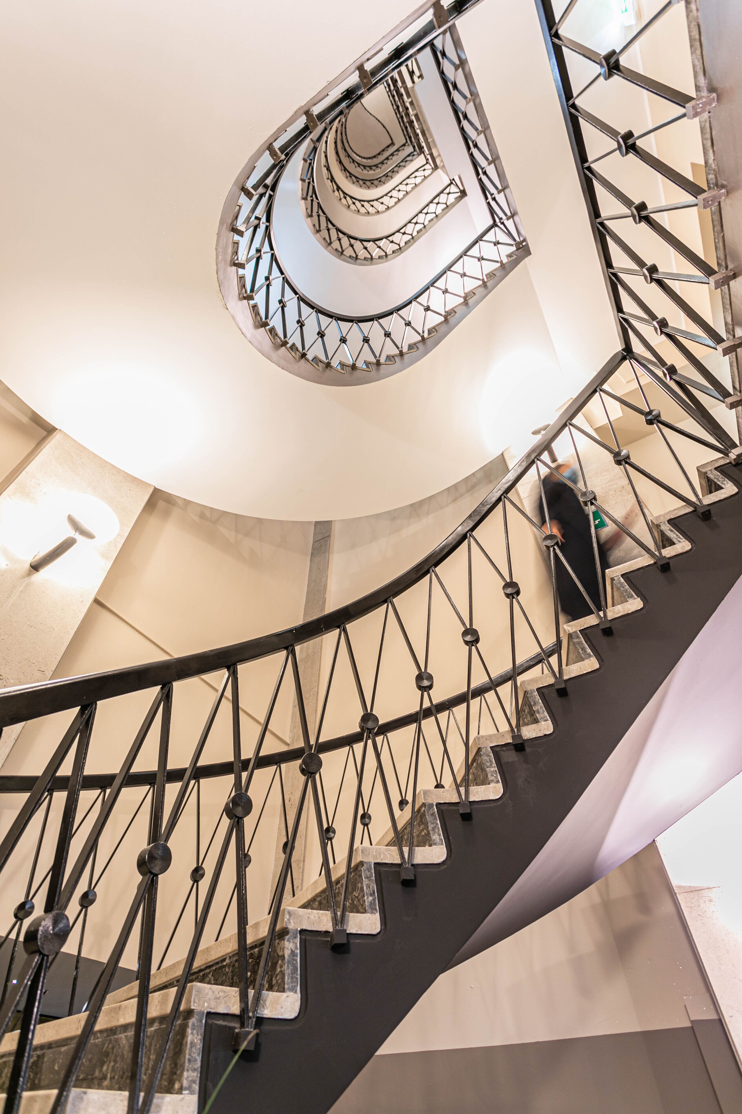 A spiral staircase with a metal railing and a central light fixture.