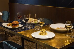 Een eettafel met borden eten, glazen wijn en bestek.