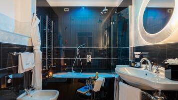 A modern bathroom with a large mirror, two sinks, a bidet, and a bathtub.