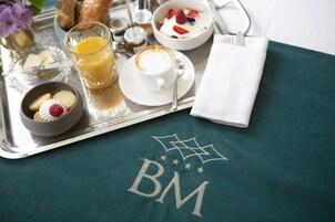 A breakfast tray with a cup of coffee, a bowl of yogurt with fruits, a glass of orange juice, and a small bowl of cookies.