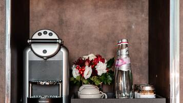 A coffee machine, a bottle, and a vase with flowers in a cabinet.