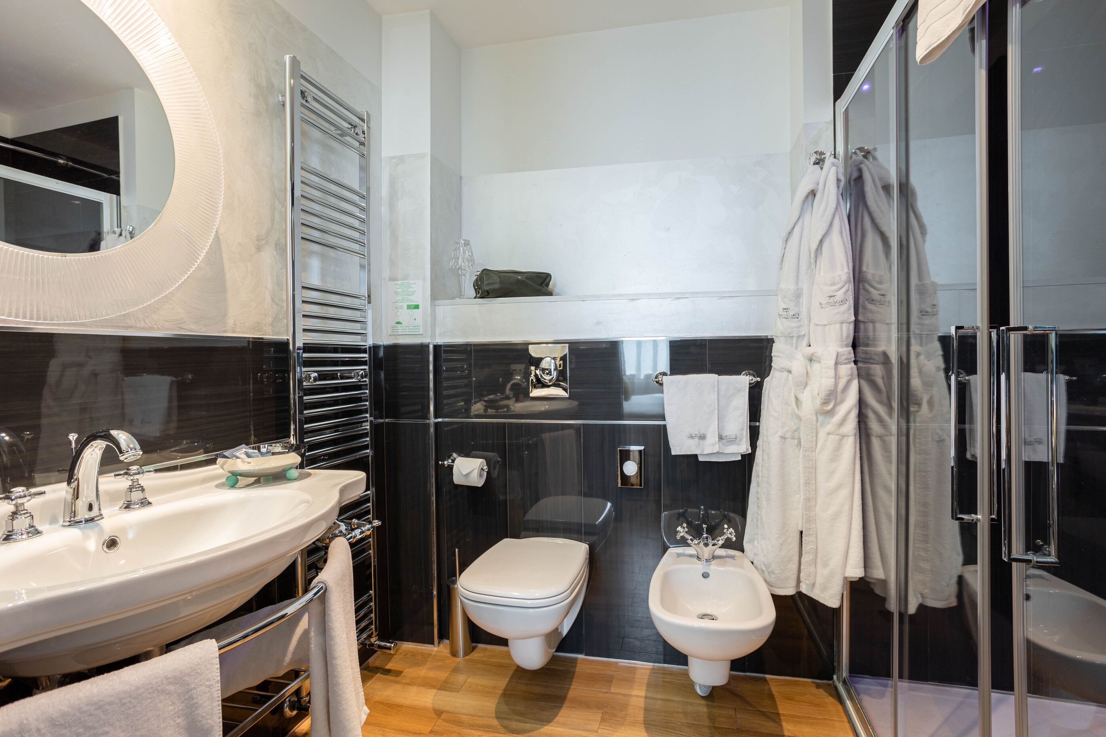 A modern bathroom with a large mirror, a sink, a toilet, a bidet, and a glass-enclosed shower area.