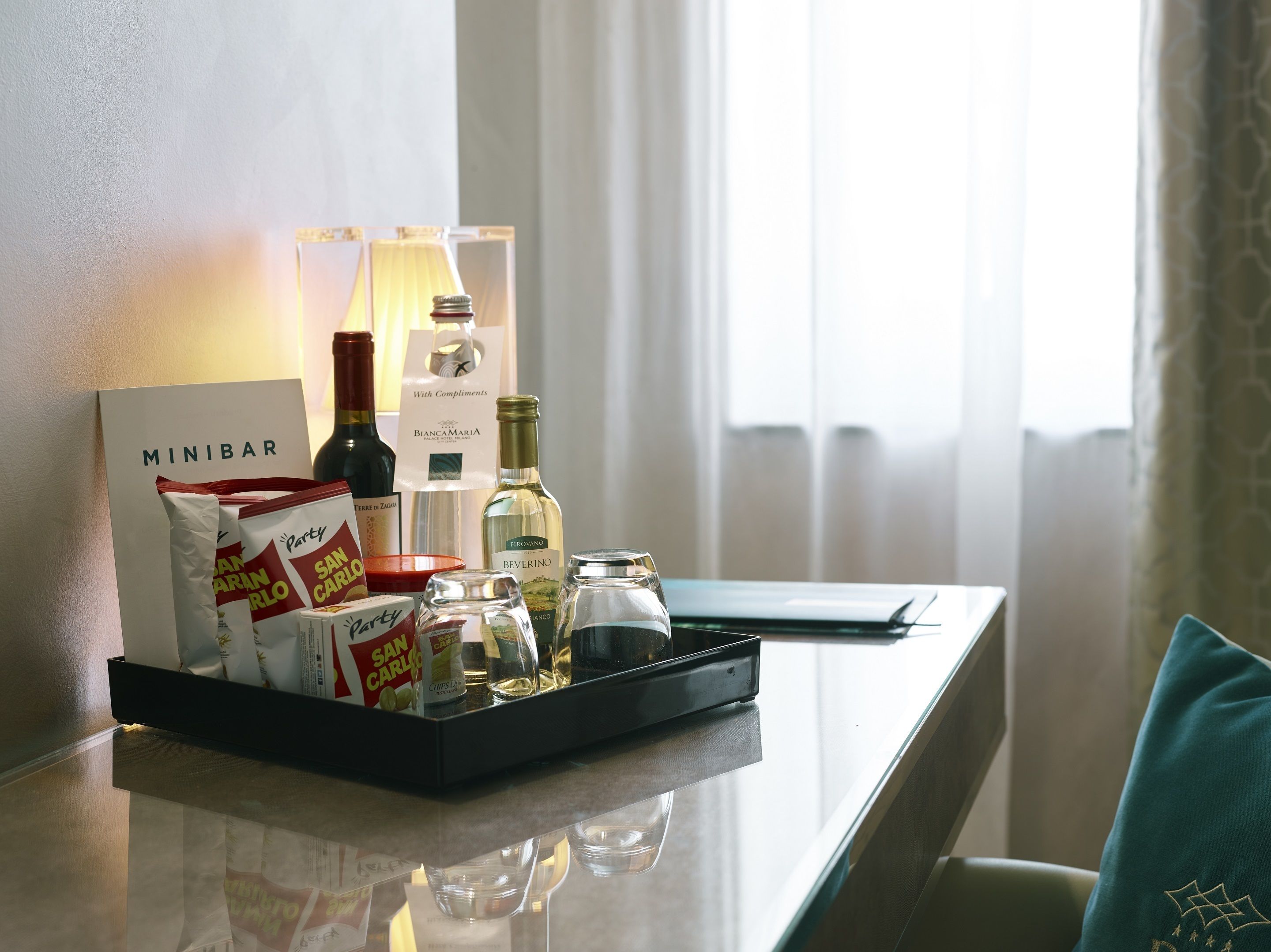 A minibar with snacks, wine bottles, and a lamp.