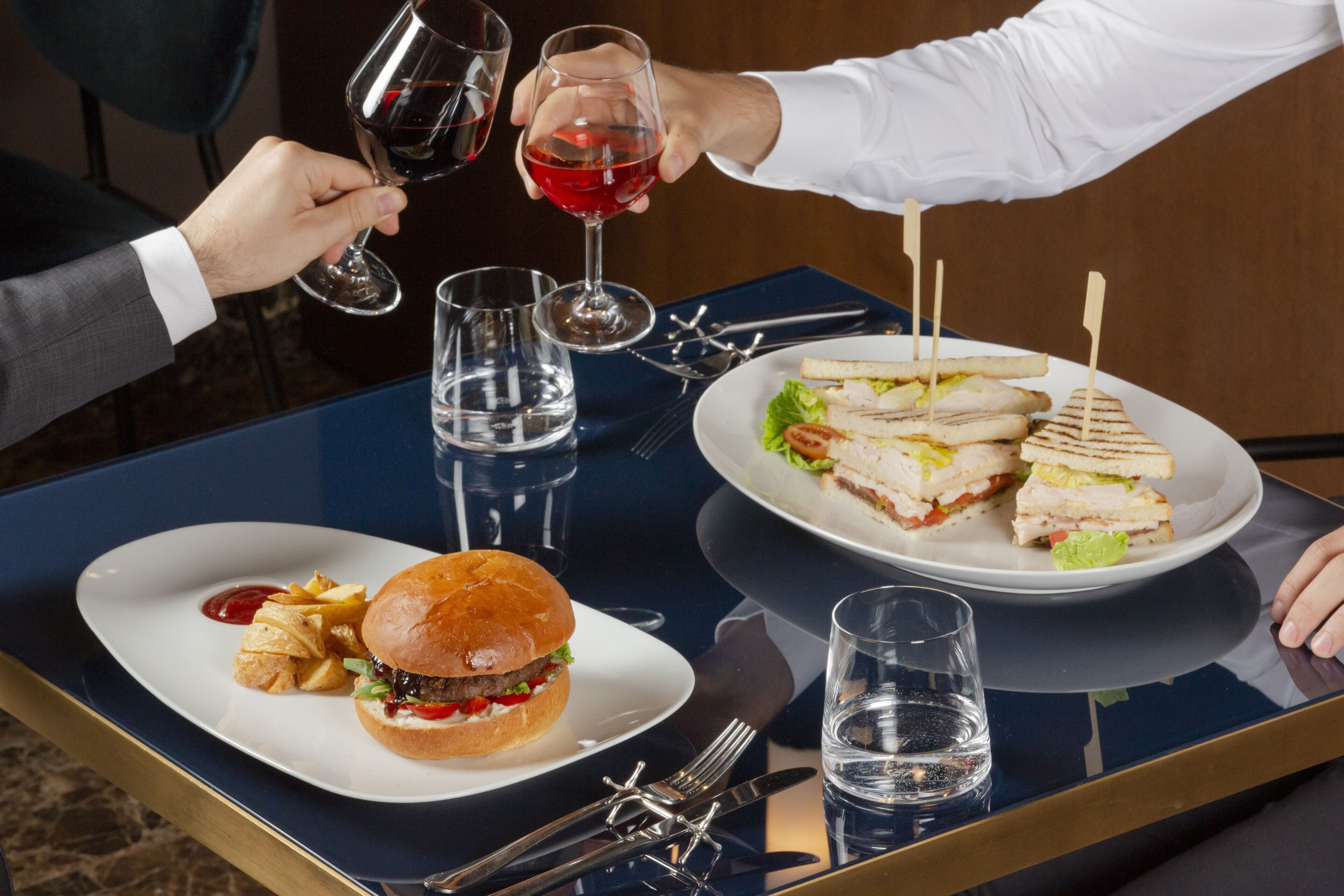 A dining table with a burger, fries, and a sandwich.