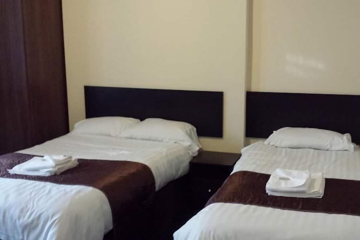 Two single beds with dark headboards and white bedding, each with a folded towel on the bed.