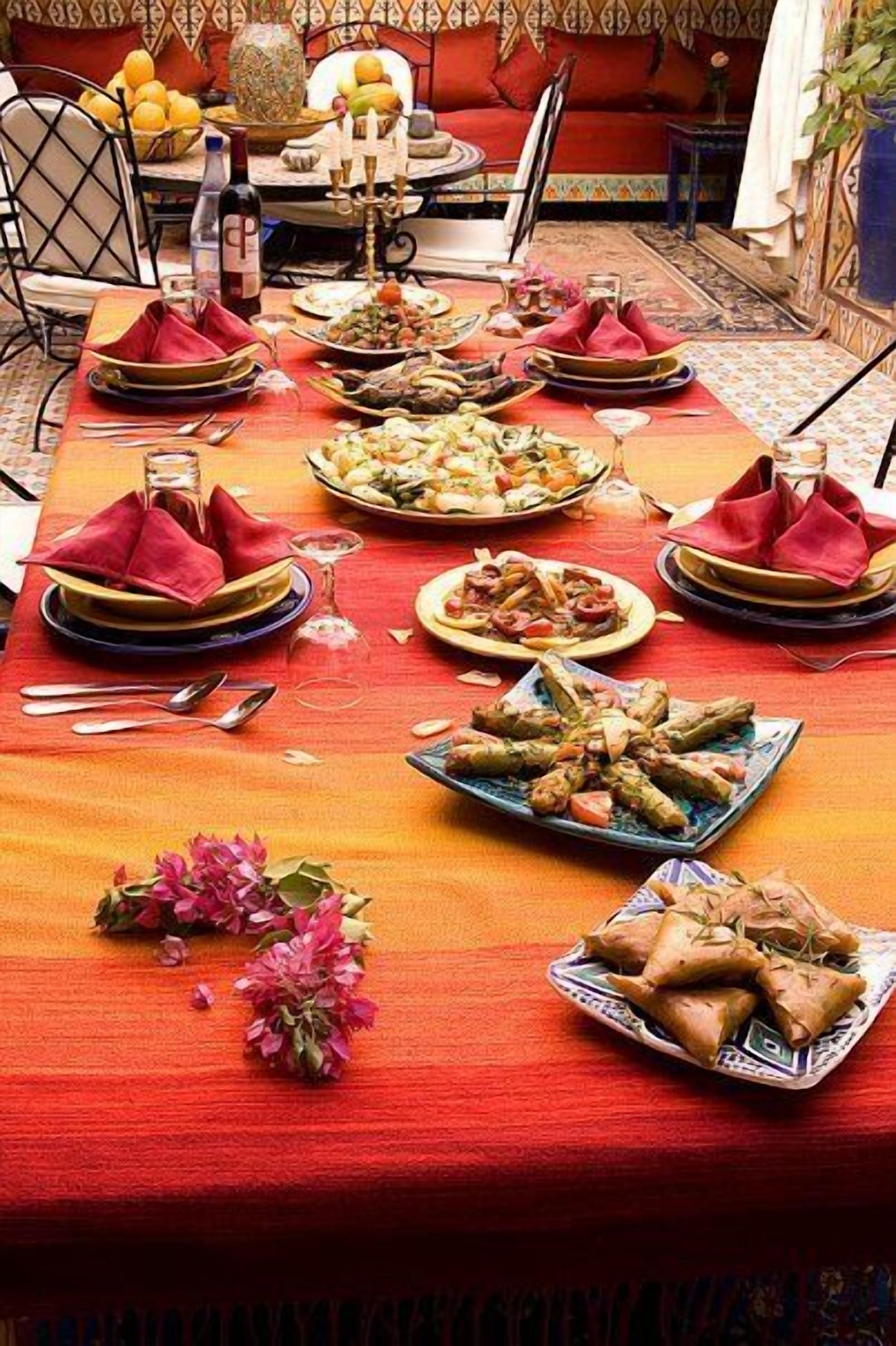 A dining table set with various dishes, a vase of flowers, and a bottle of wine.