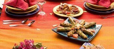 A dining table set with various dishes, a vase of flowers, and a bottle of wine.