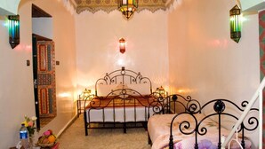 A bedroom with a bed, decorative wall sconces, and a patterned ceiling. - Riad Maryam (Taroudant)