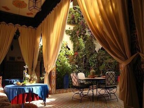 Un comedor con una mesa y sillas, rodeado de cortinas y plantas.
