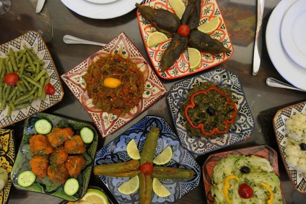 A table with various dishes, including a plate with green beans, a dish with a lemon garnish, and others with different garnishes.