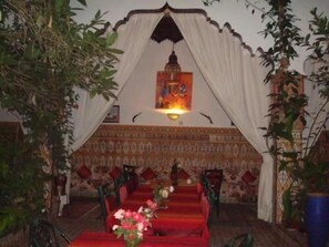 A room with a red carpeted area, a white canopy, and a patterned wall. - Riad Maryam (Taroudant)