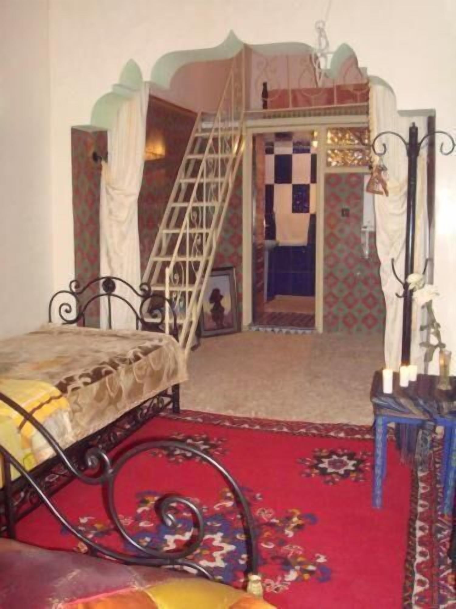 Una camera da letto con un letto, una scala, un tavolino e una sedia.