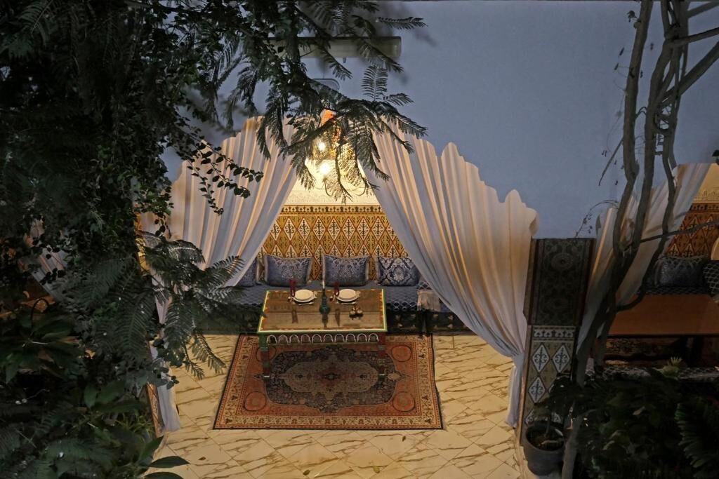 A cozy seating area with a patterned rug, a table with a decorative centerpiece, and a canopy overhead.