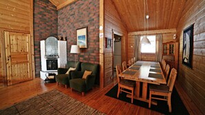 A cozy cabin interior with a fireplace, a dining table, and a comfortable seating area. - Villa Struka (Pyhtaa)