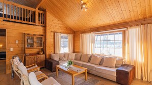 A wooden interior with a sofa, chairs, a coffee table, and a cabinet. - Villa Struka (Pyhtaa)