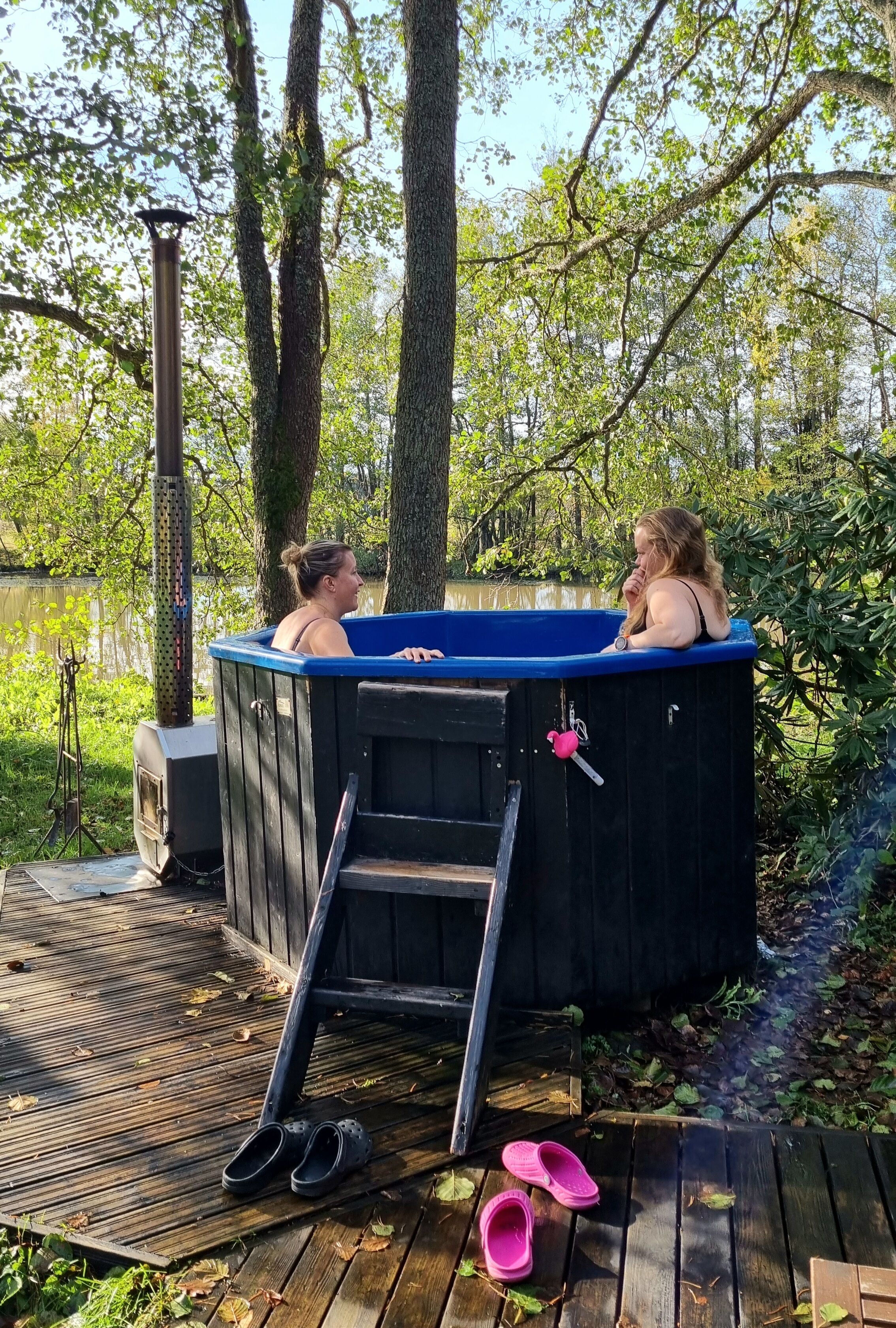 Terraza de madera con un jacuzzi, una escalera y un par de zapatos.
