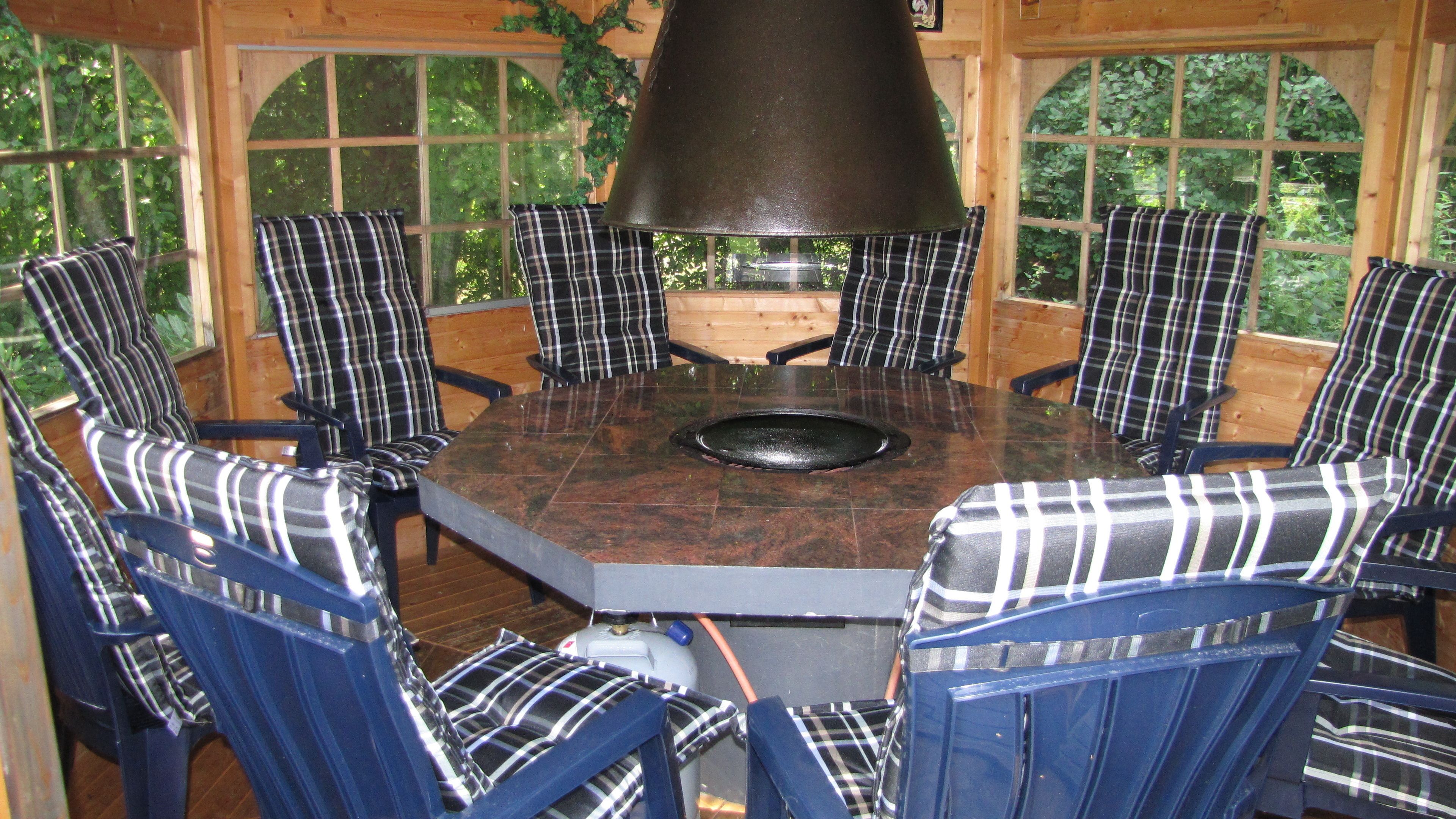 Une table ronde avec un foyer central, entourée de chaises à motifs écossais.