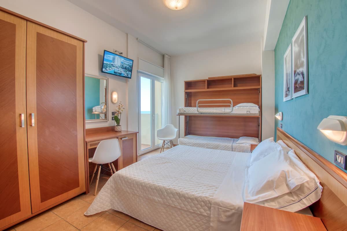 A hotel room with a bed, a desk, a chair, a TV, and a wardrobe.