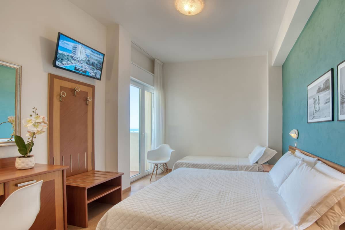 A hotel room with a bed, a desk, a chair, a television, and a window.